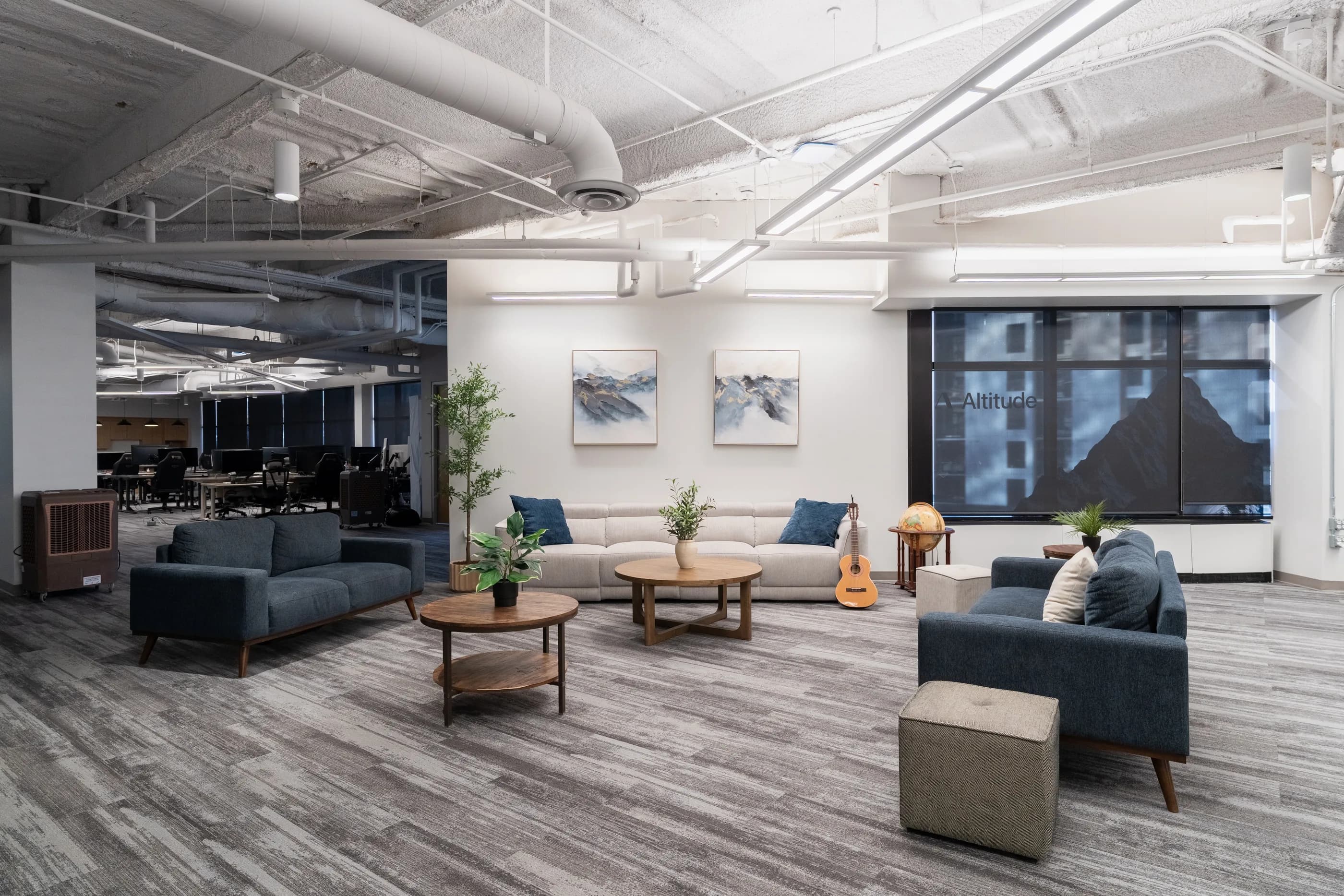 Long view through the furnished open workspace with windows and white industrial ceilings